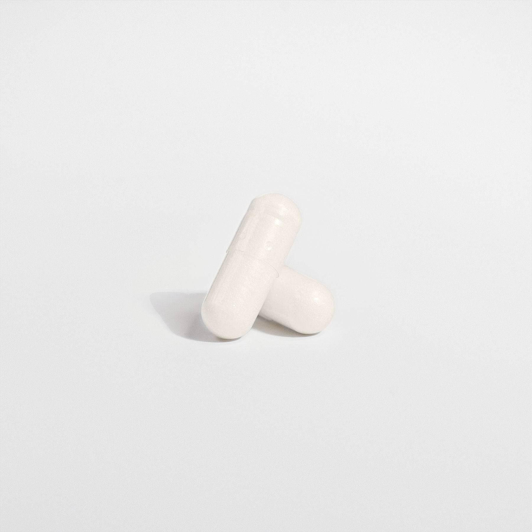 Close-up of two white 5-HTP capsules, formulated to support serotonin levels and emotional well-being naturally.