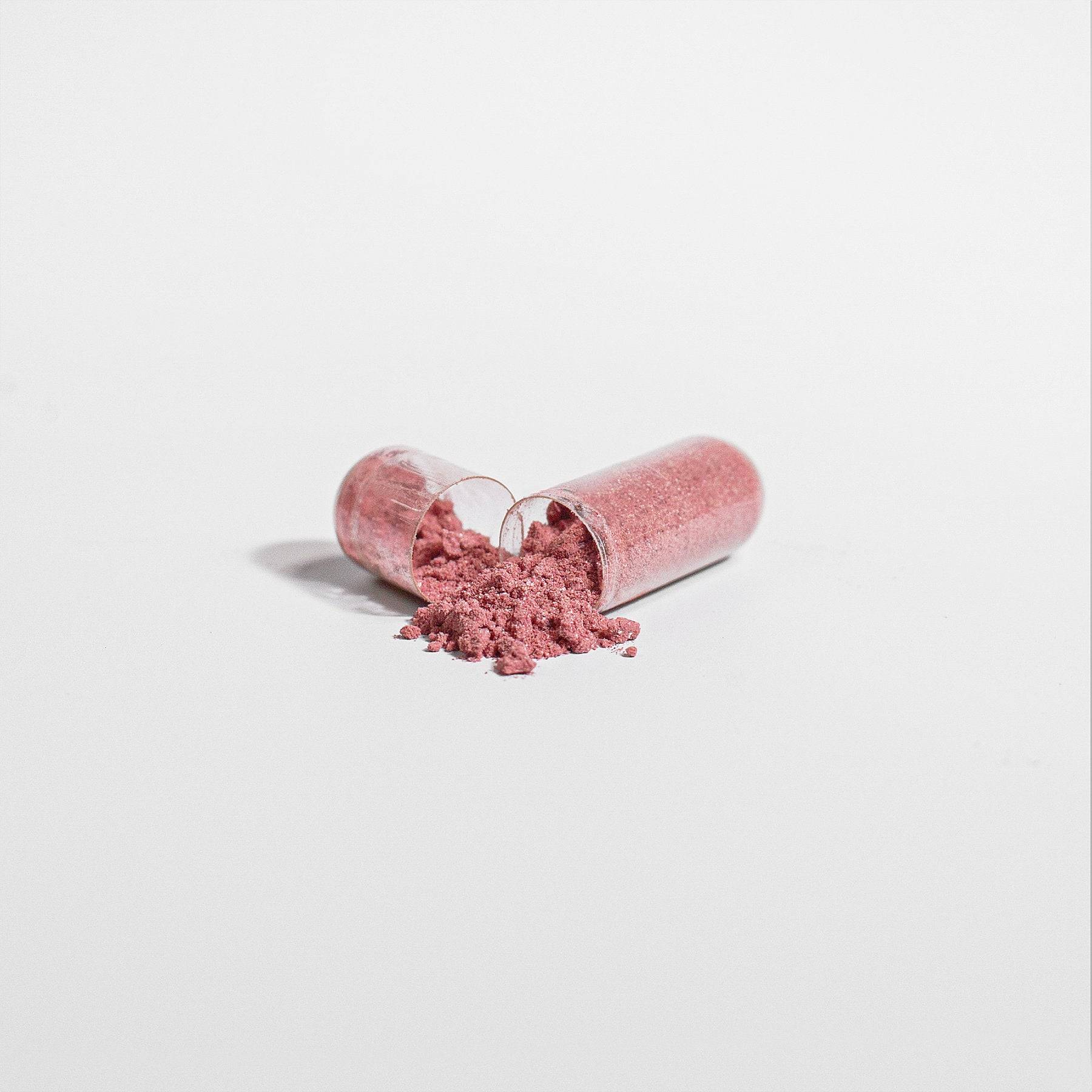 Opened beetroot capsule spilling fine pink powder, showcasing the natural beetroot extract content for energy and endurance.